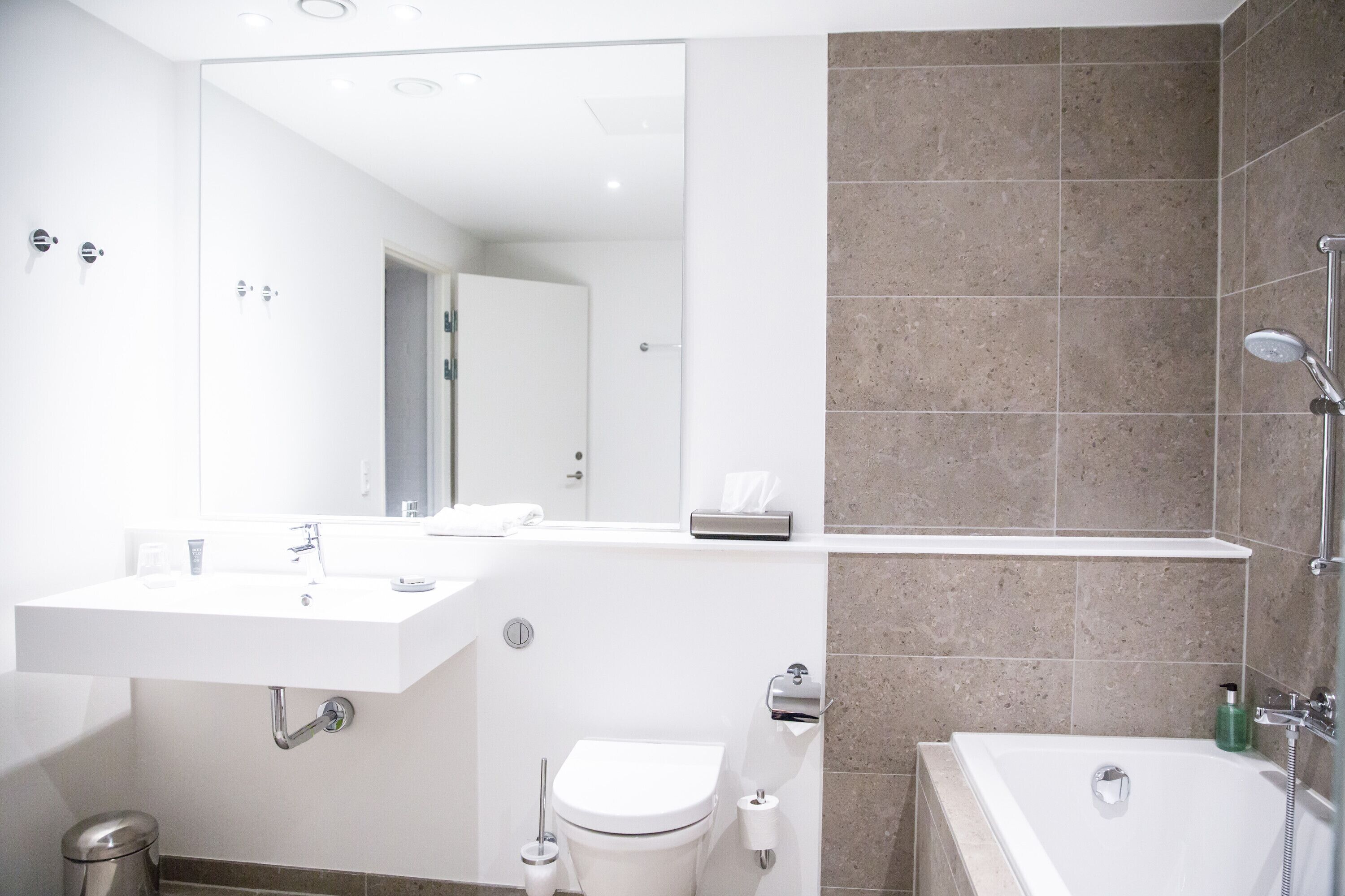 Un baño moderno con lavamanos, inodoro y bañera blancos.