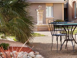 Un patio con mesa y sillas, una fuente de piedra y una palmera.