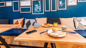 Une table en bois dressée pour le petit-déjeuner, avec une assiette de toasts, une tasse de café et un smartphone.