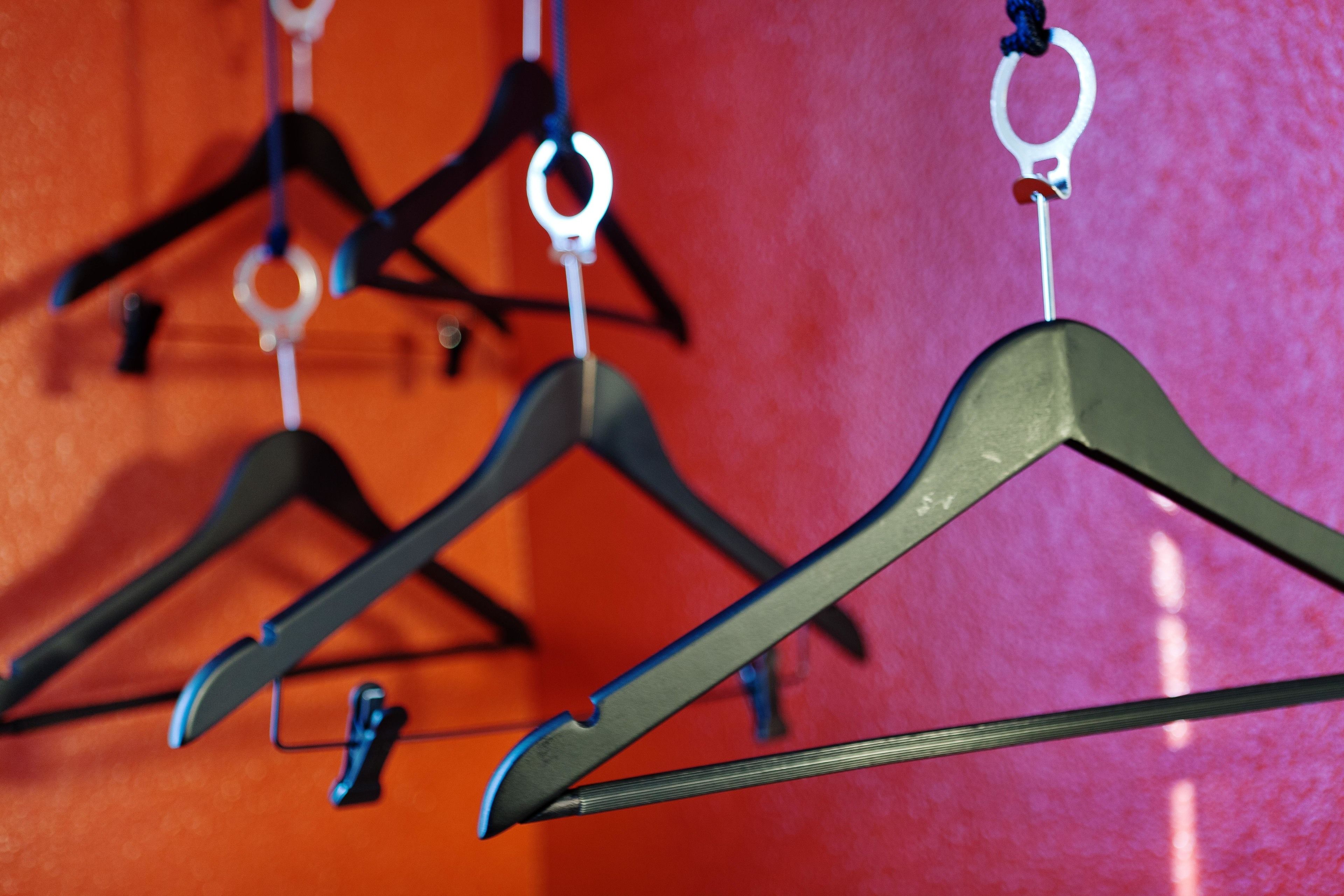 A rack of hanging clothes with a red background.