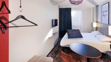 Una habitación de hotel con cama, televisión, mesa y silla.