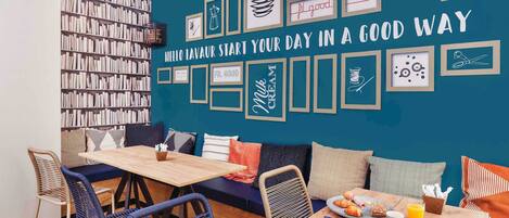 Un rincón acogedor para desayunar, con una mesa de madera, sillas y una estantería llena de libros.