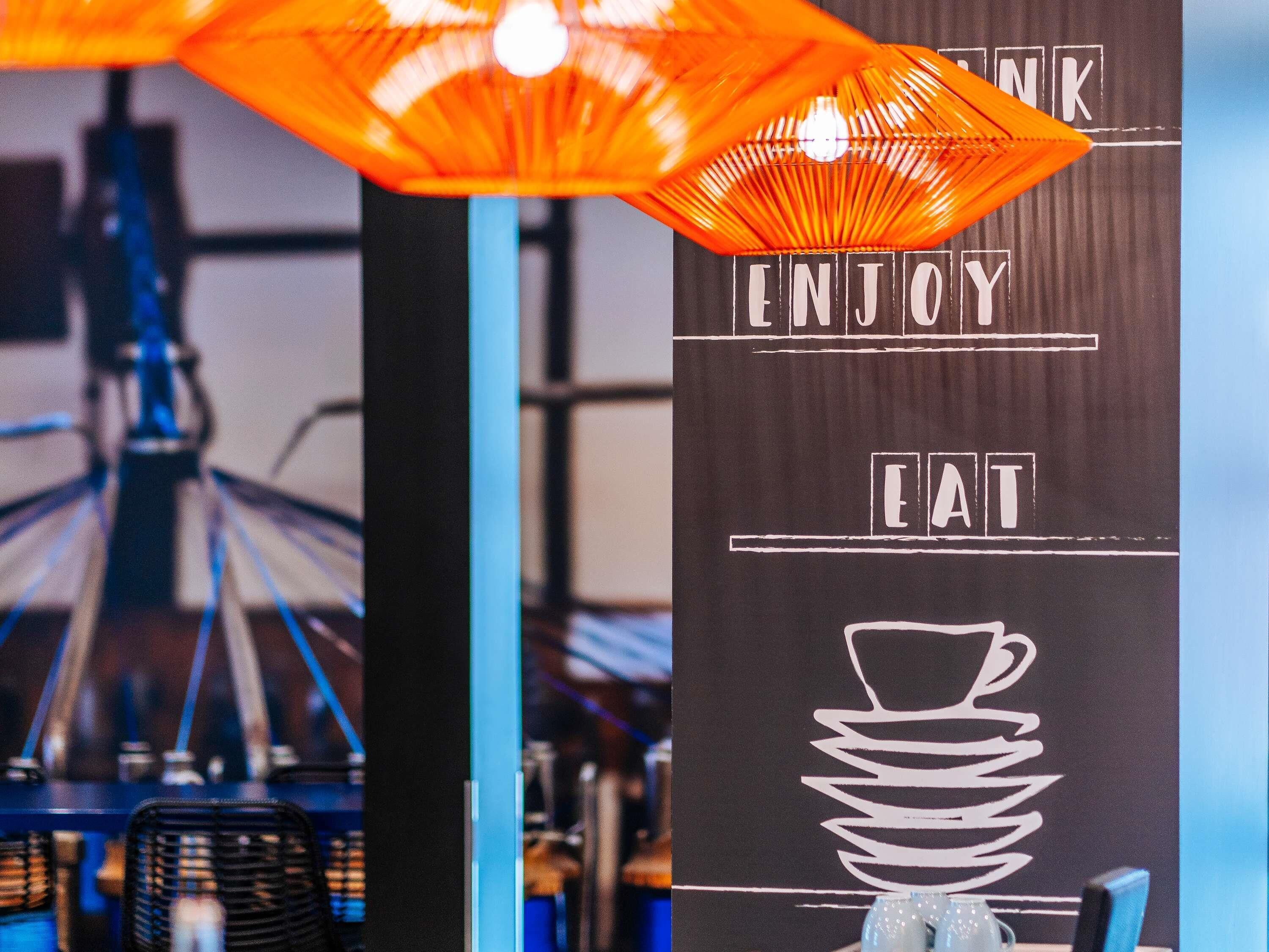 A wall with the words 'ENJOY' and 'EAT' and a cup stack graphic.