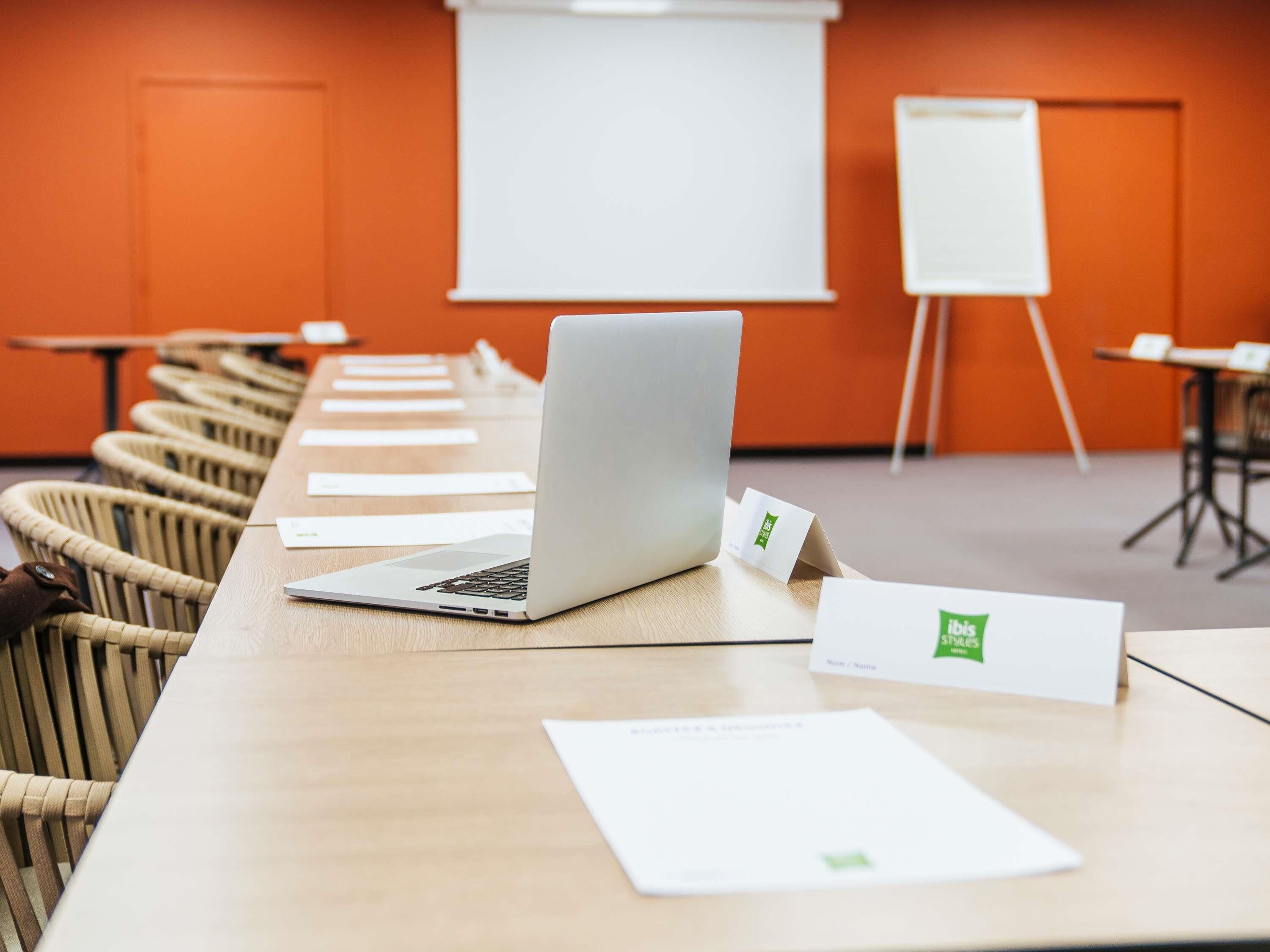 A conference room with a long table, laptops, name tags, and a whiteboard.