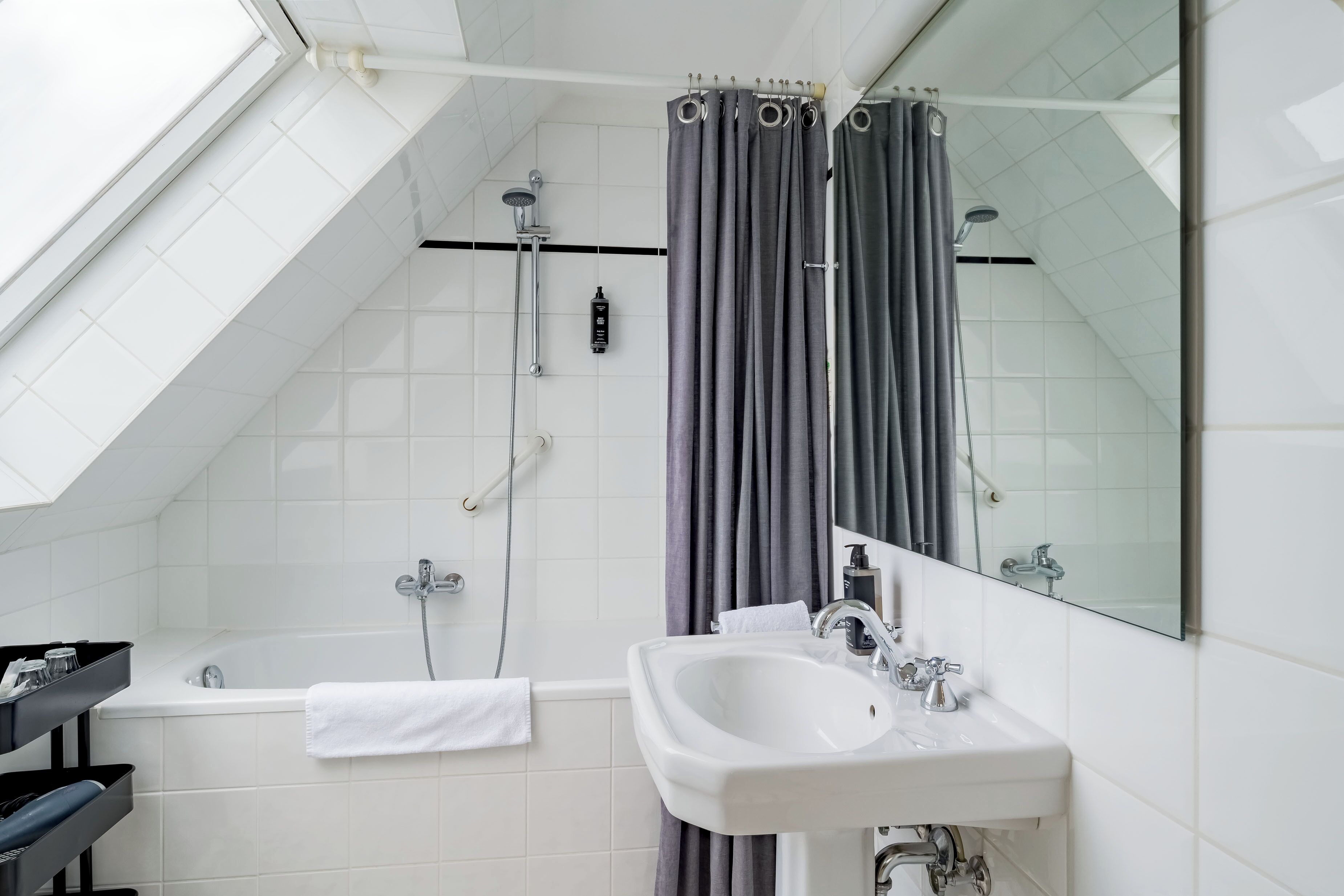 A modern bathroom with a skylight, a bathtub, a shower, and a sink.