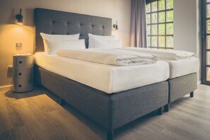 A modern bedroom with a large bed, a bedside lamp, and a window with curtains.