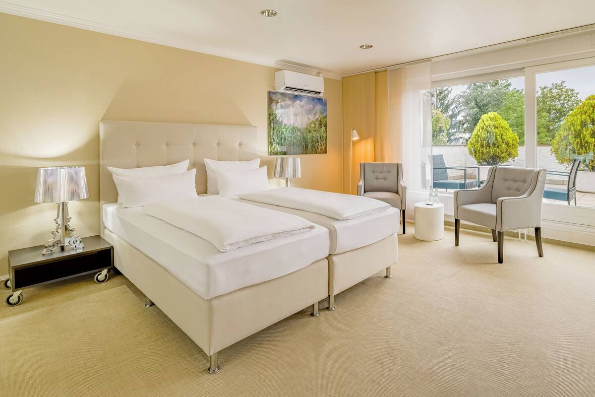 A hotel room with a large bed, a chair, a lamp, and a view of the outdoors.