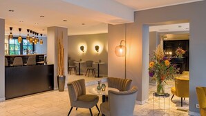A modern hotel lobby with a reception desk, seating area, and decorative lighting. - rugs HOTEL Köln (Cologne)