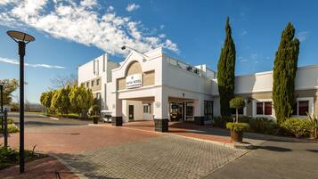 Un hotel con fachada blanca, entrada abovedada y un letrero que dice 'HOTEL STELLENBOSCH'.
