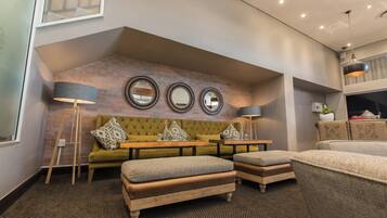 A modern living room with a brick accent wall, a green sofa, two ottomans, and a coffee table.