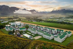 Un grand complexe hôtelier comprenant plusieurs bâtiments, une piscine et offrant une vue sur les montagnes et les champs environnants.