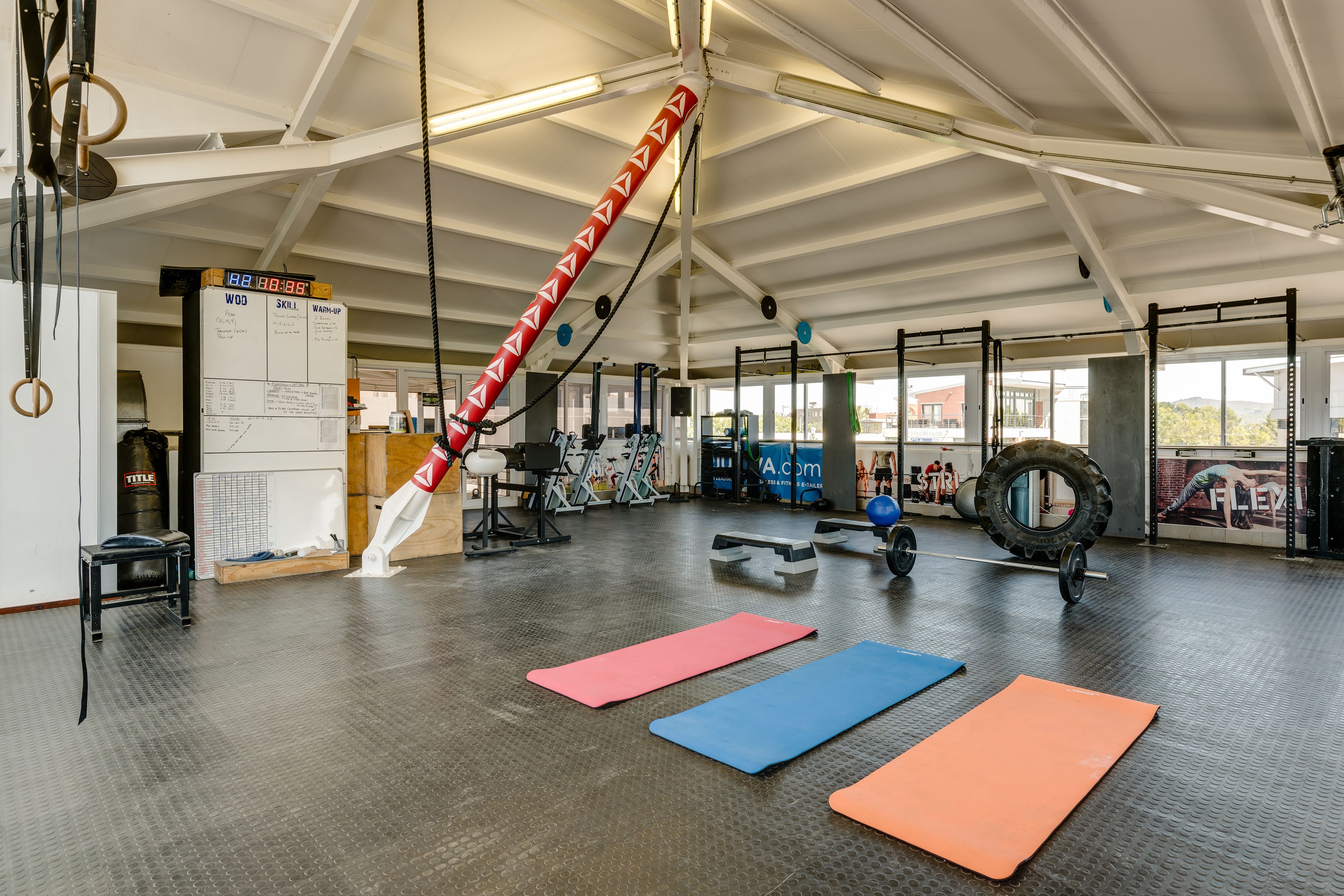 Uma academia com equipamentos de exercícios, colchonetes e um cronômetro digital.