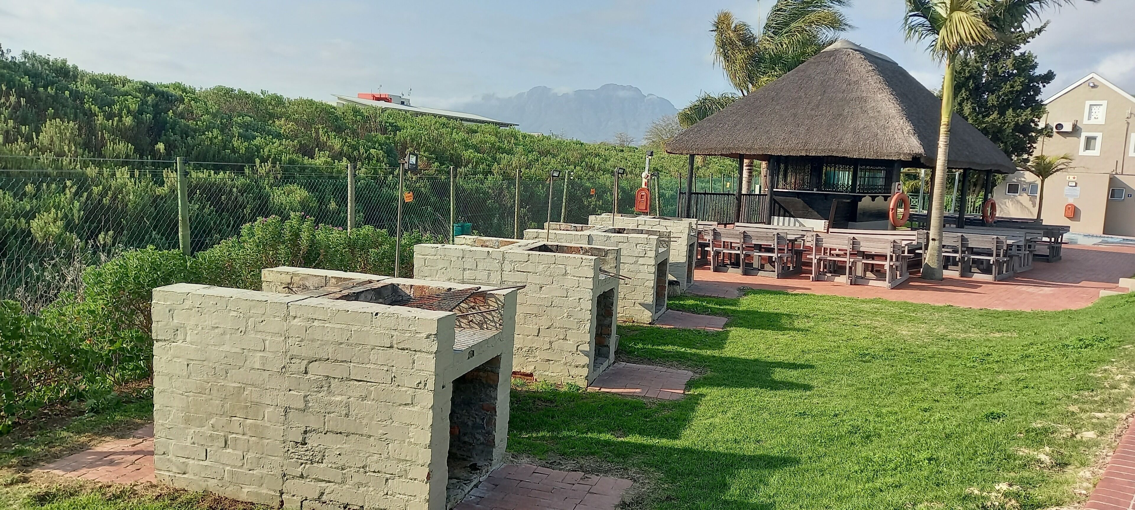 A patio area with stone planters, a thatched-roof structure, and outdoor seating.