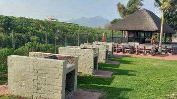 A patio area with stone planters, a thatched-roof structure, and outdoor seating.
