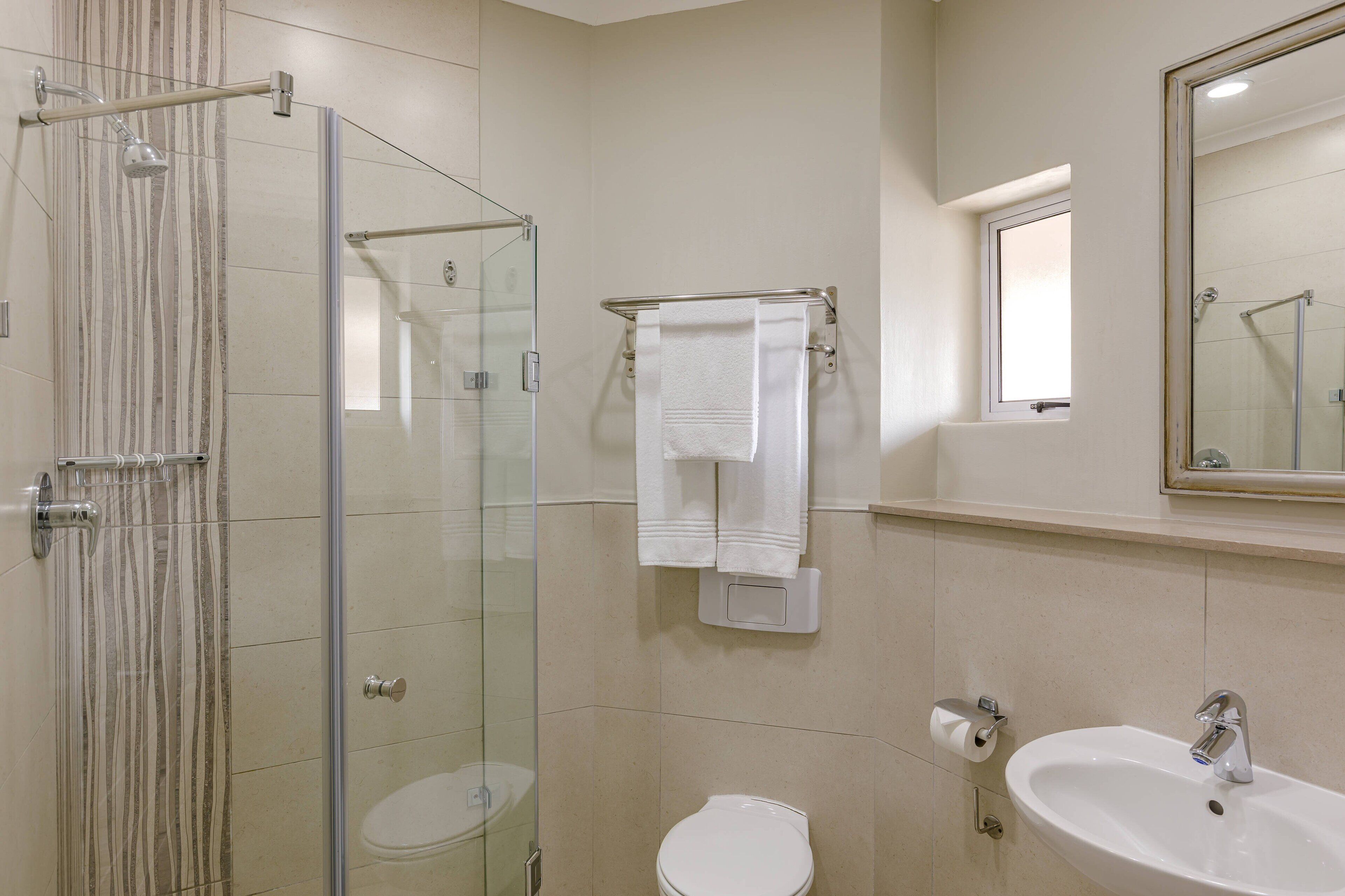 A bathroom with a glass-enclosed shower, a toilet, and a sink.