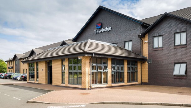 Un hôtel Travelodge au design moderne, caractérisé par une façade en briques et de grandes fenêtres.