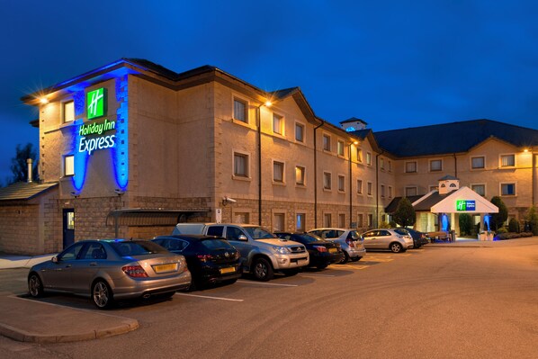 A Holiday Inn Express hotel with a parking lot filled with cars.