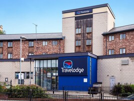 Un hotel Travelodge con fachada moderna, grandes ventanales y un llamativo letrero azul.