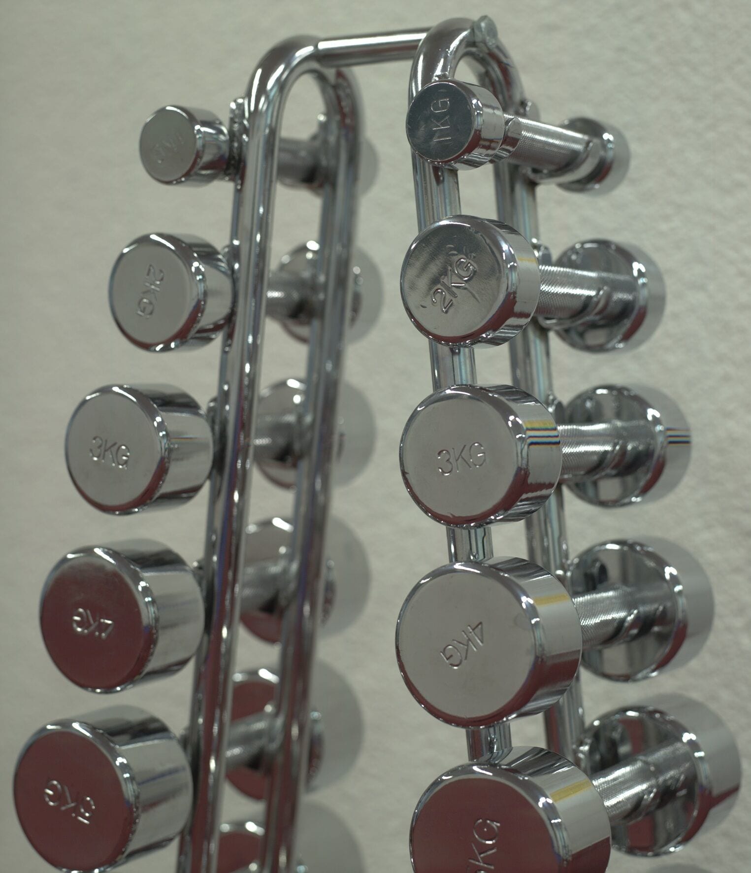 Un juego de mancuernas de 3 kilogramos montadas en un soporte de pared.