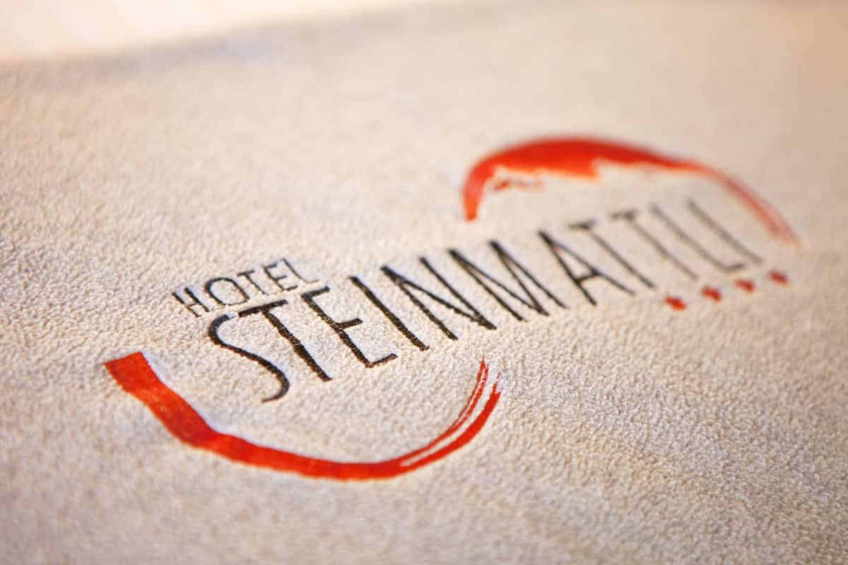 A close-up of a hotel name, HOTEL STEINMATTU, on a textured surface.