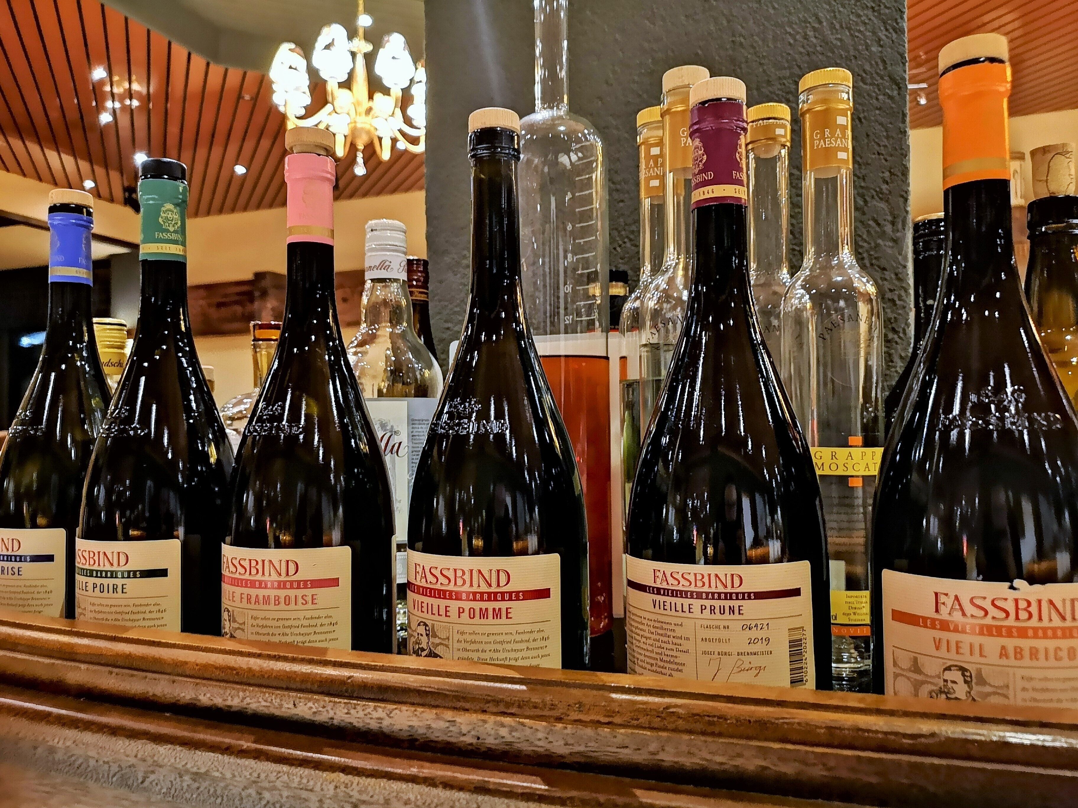 A selection of wine bottles on a shelf, including brands like Fassbind and Grapp Moscat.