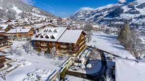 A snow-covered mountain town with wooden buildings and a ski resort. - Hotel Steinmattli (Adelboden)