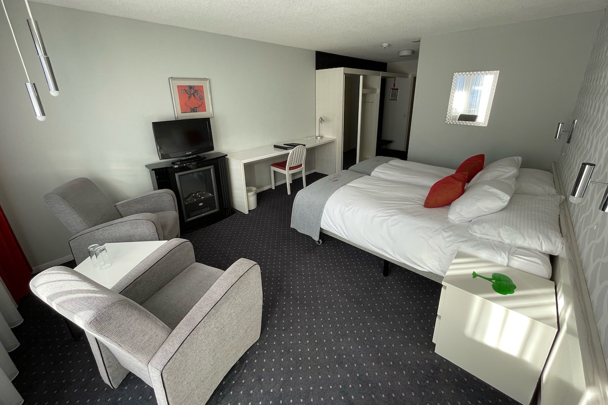 A hotel room with a bed, a desk, a television, and a chair.