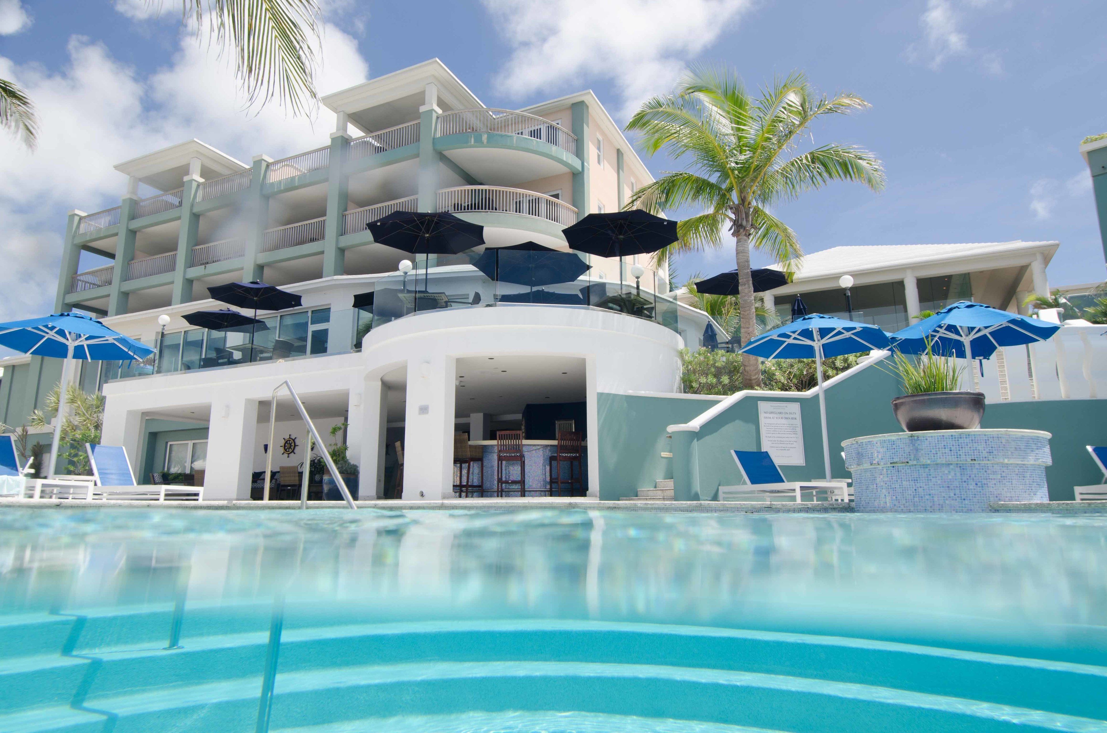 A hotel with a pool, outdoor seating, and a multi-story building with balconies.