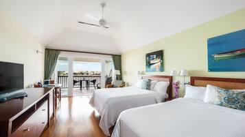 A hotel room with two beds, a TV, a desk, and a balcony with a view.