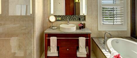 A bathroom with a vanity, sink, mirror, and bathtub.