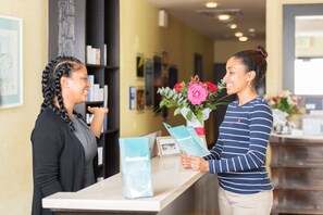 A reception desk with a counter, a vase with flowers, and a brochure.