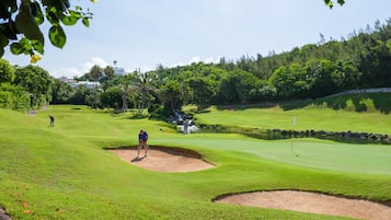 Un campo de golf con un búnker, un obstáculo acuático y un marcador de bandera.