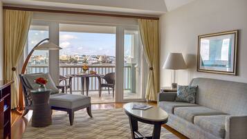 A spacious living room with a balcony, a sofa, a coffee table, and a chair with a vase of flowers.