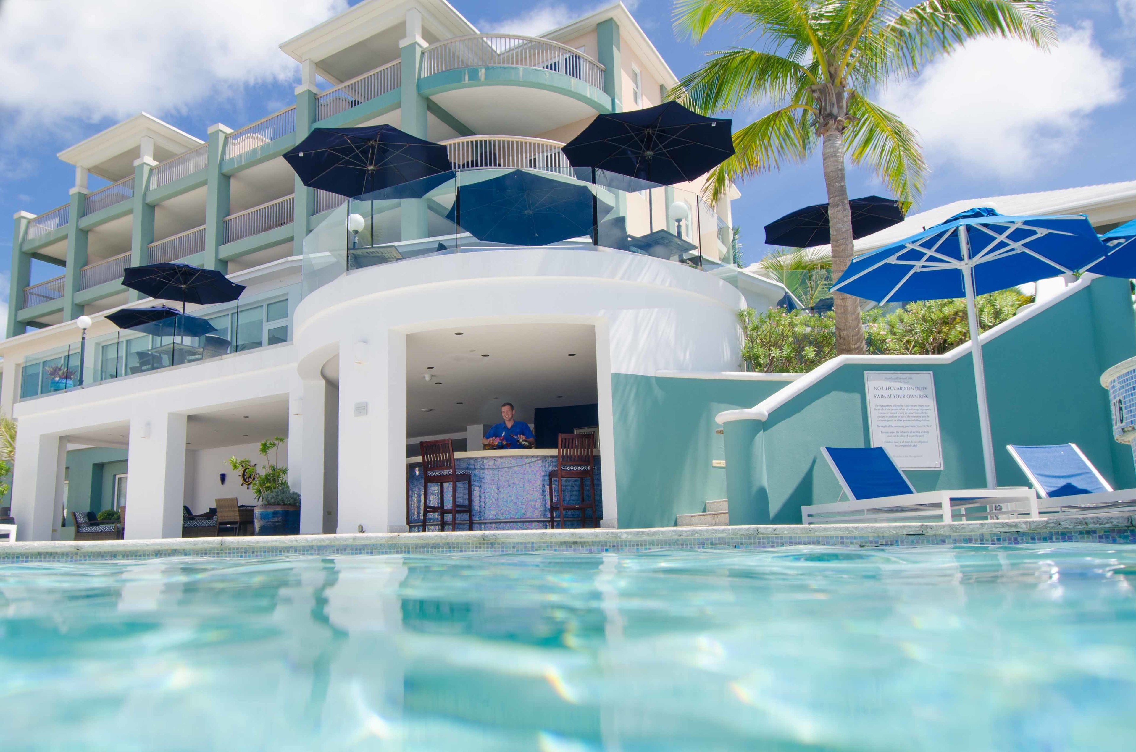 Un espace aménagé au bord de la piscine, comprenant un bar, des chaises longues et des parasols.