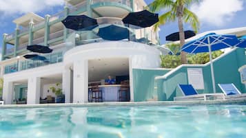 Un espace aménagé au bord de la piscine, comprenant un bar, des chaises longues et des parasols.