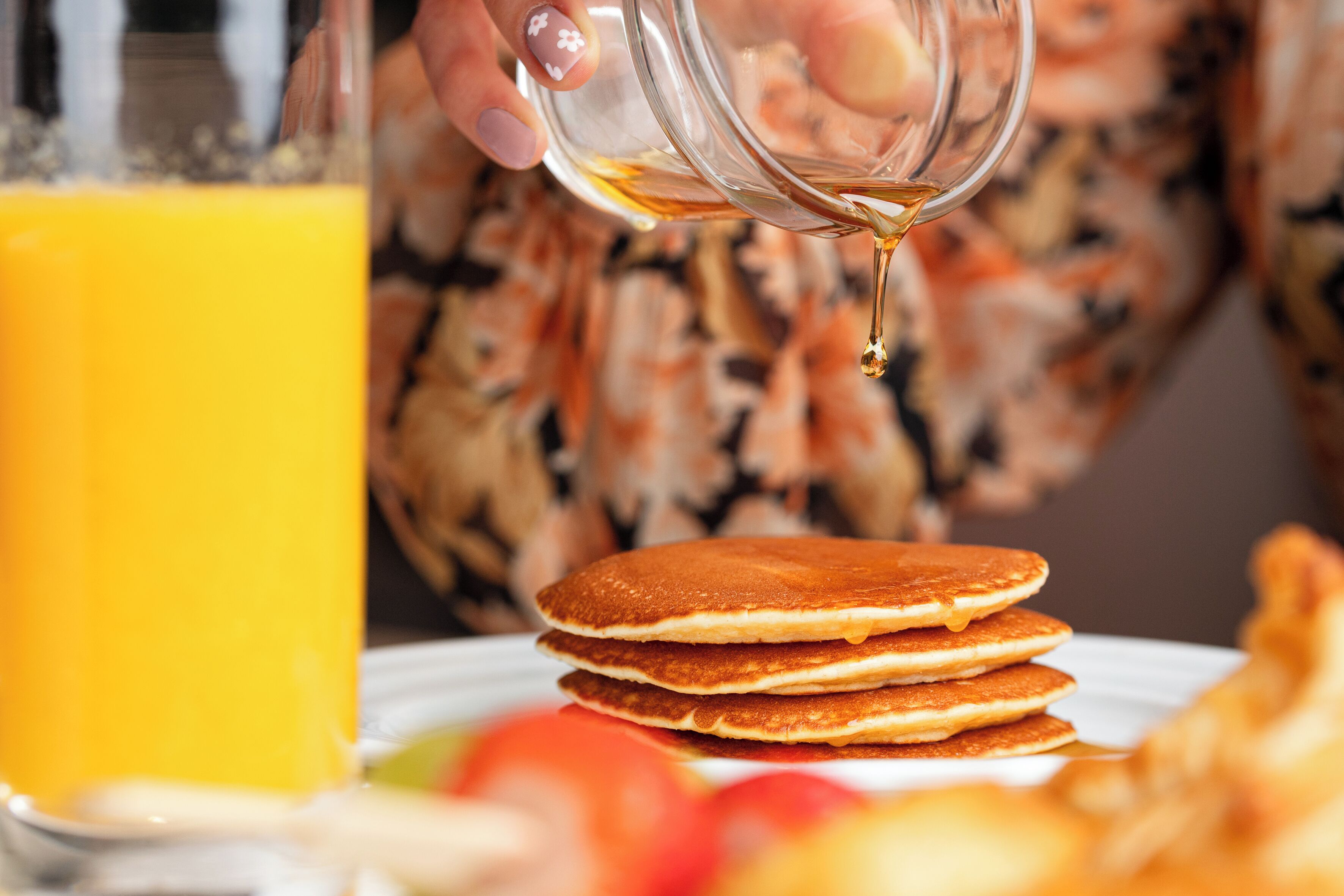 Ein Stapel Pfannkuchen, über den Sirup gegossen wird.