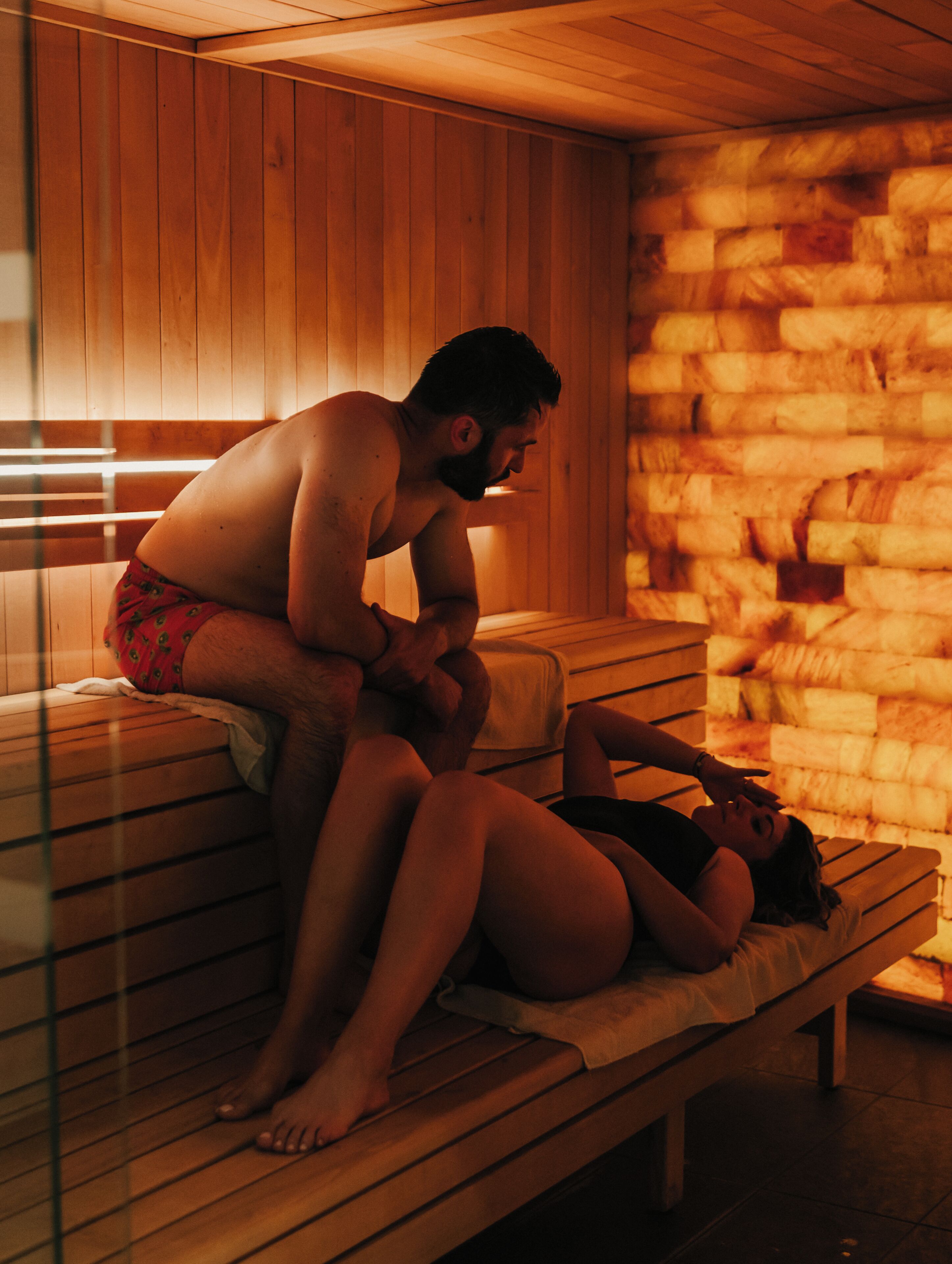 Un sauna avec des bancs en bois et un mur en pierre.