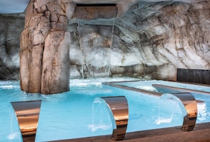 A pool area with a waterfall feature and a rocky backdrop.