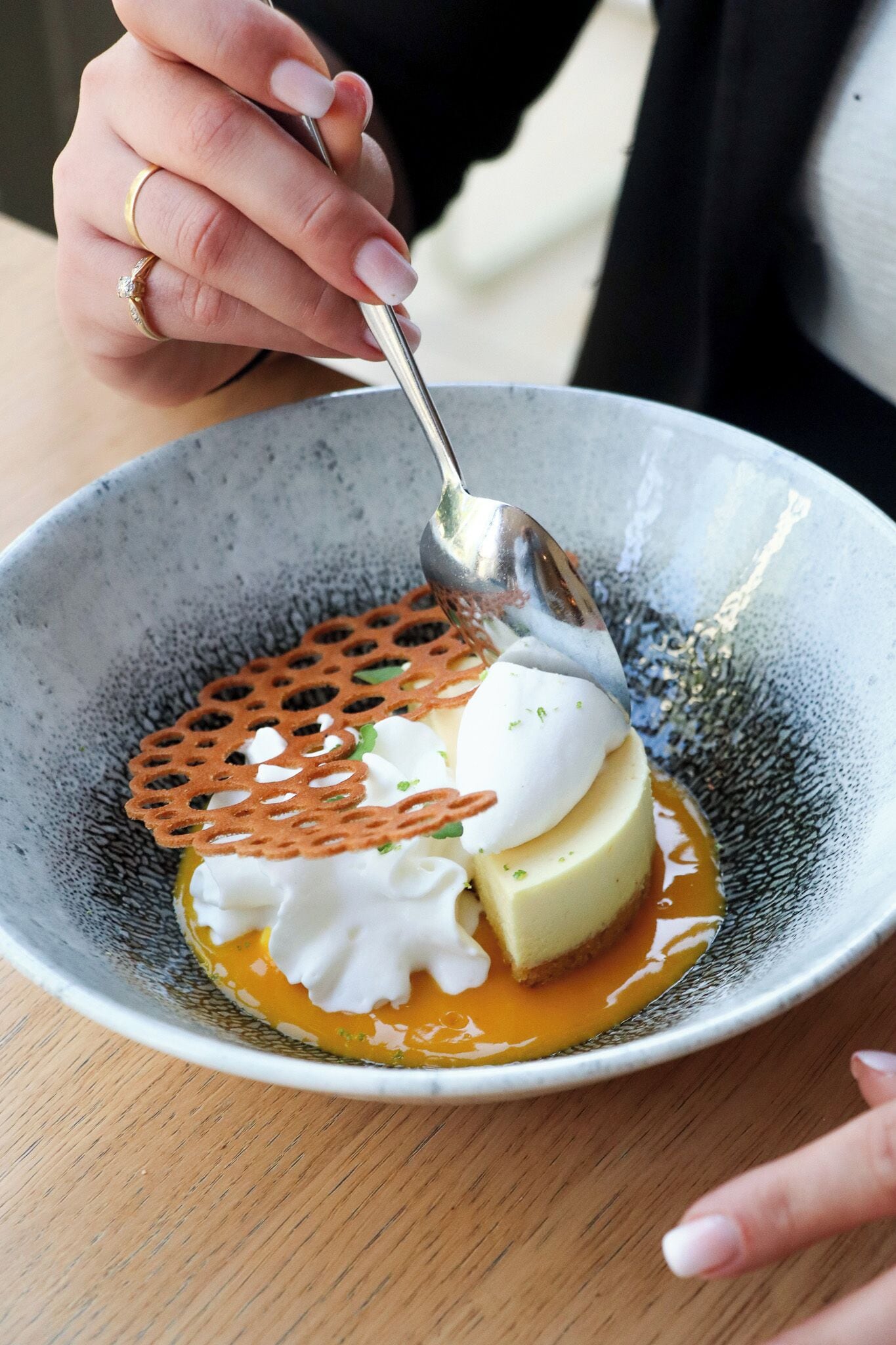 A person serving a dessert in a bowl with a spoon.