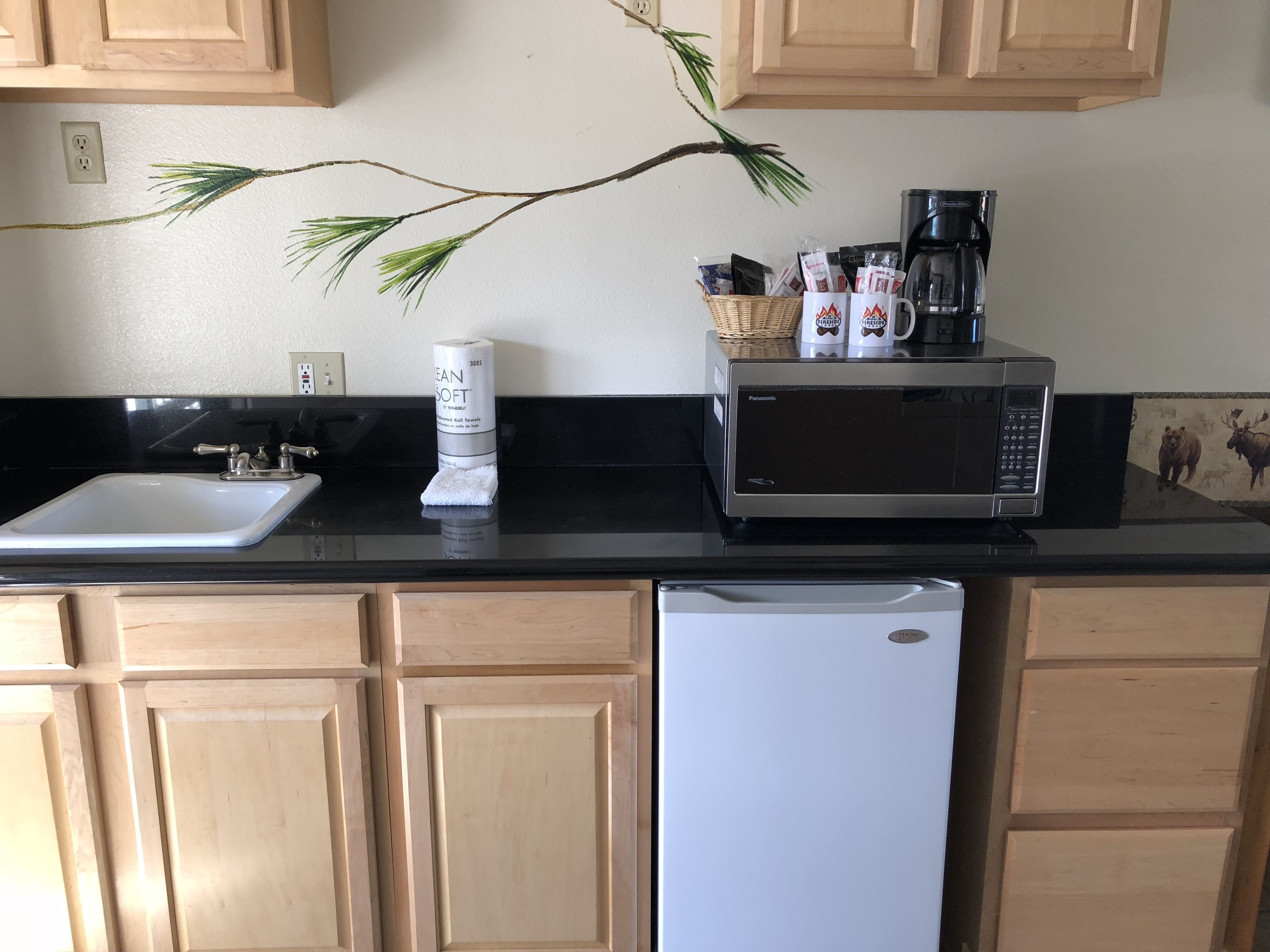 A kitchen with a sink, a microwave, a coffee maker, and a roll of paper towels.