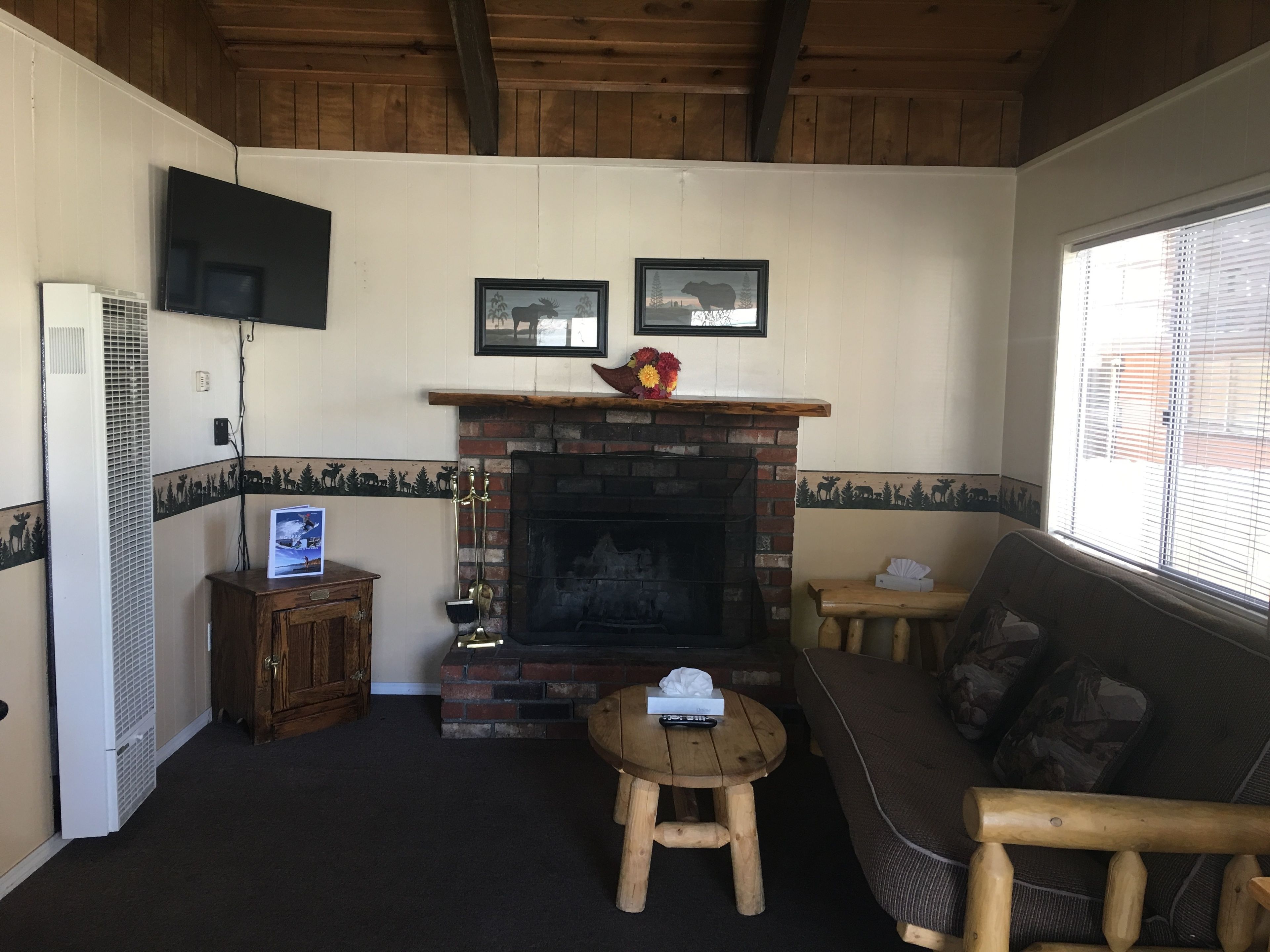 A cozy room with a fireplace, a television mounted on the wall, and a sofa.