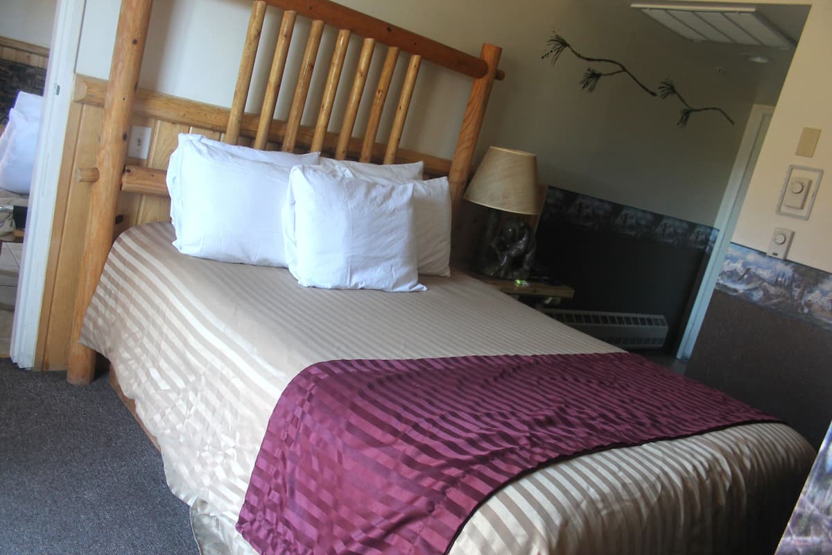 Ein Bett mit Holz-Kopfteil, weißen Kissen und einer gestreiften Tagesdecke.