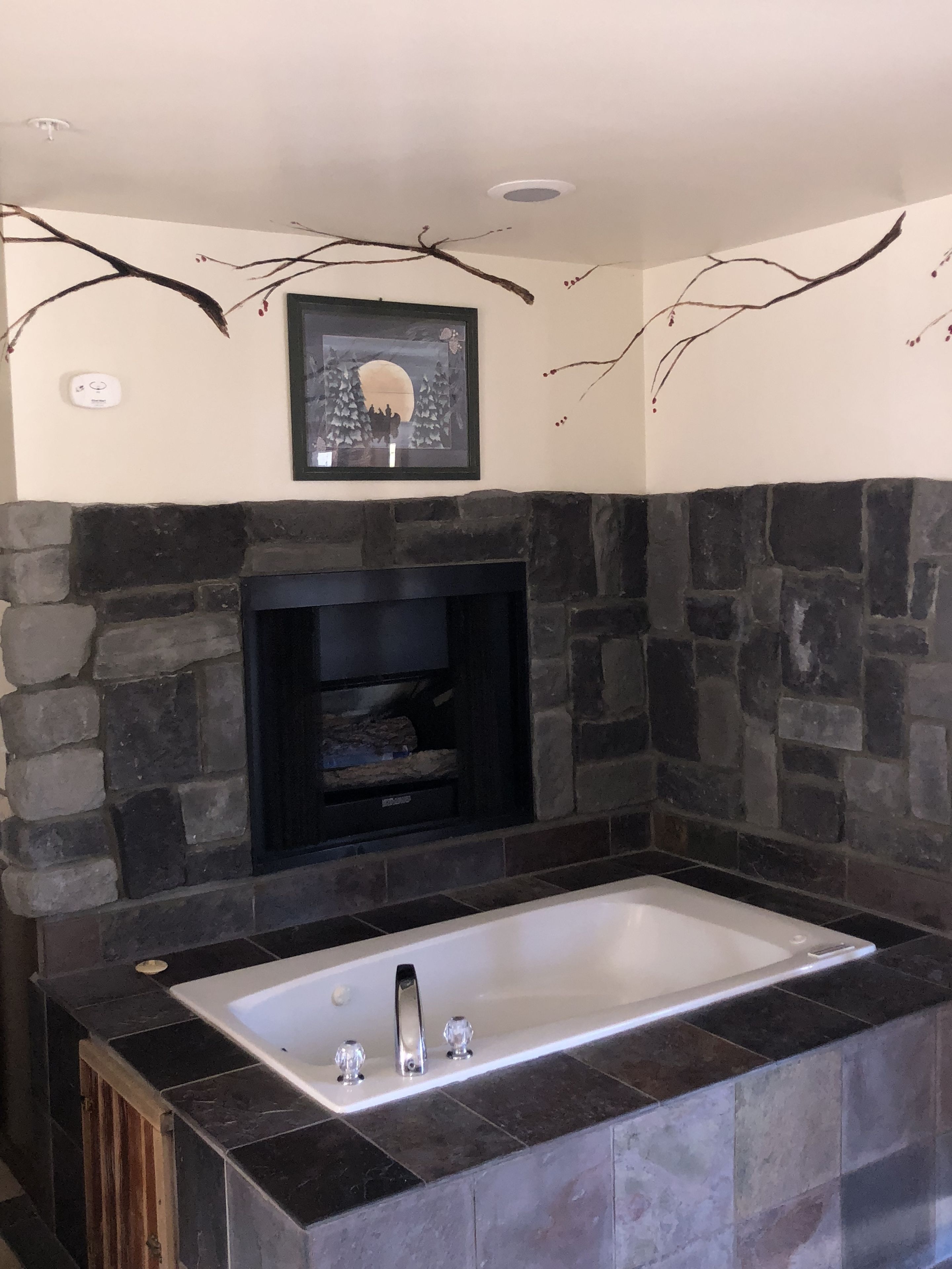 A bathroom with a stone wall, a framed picture, and a bathtub.