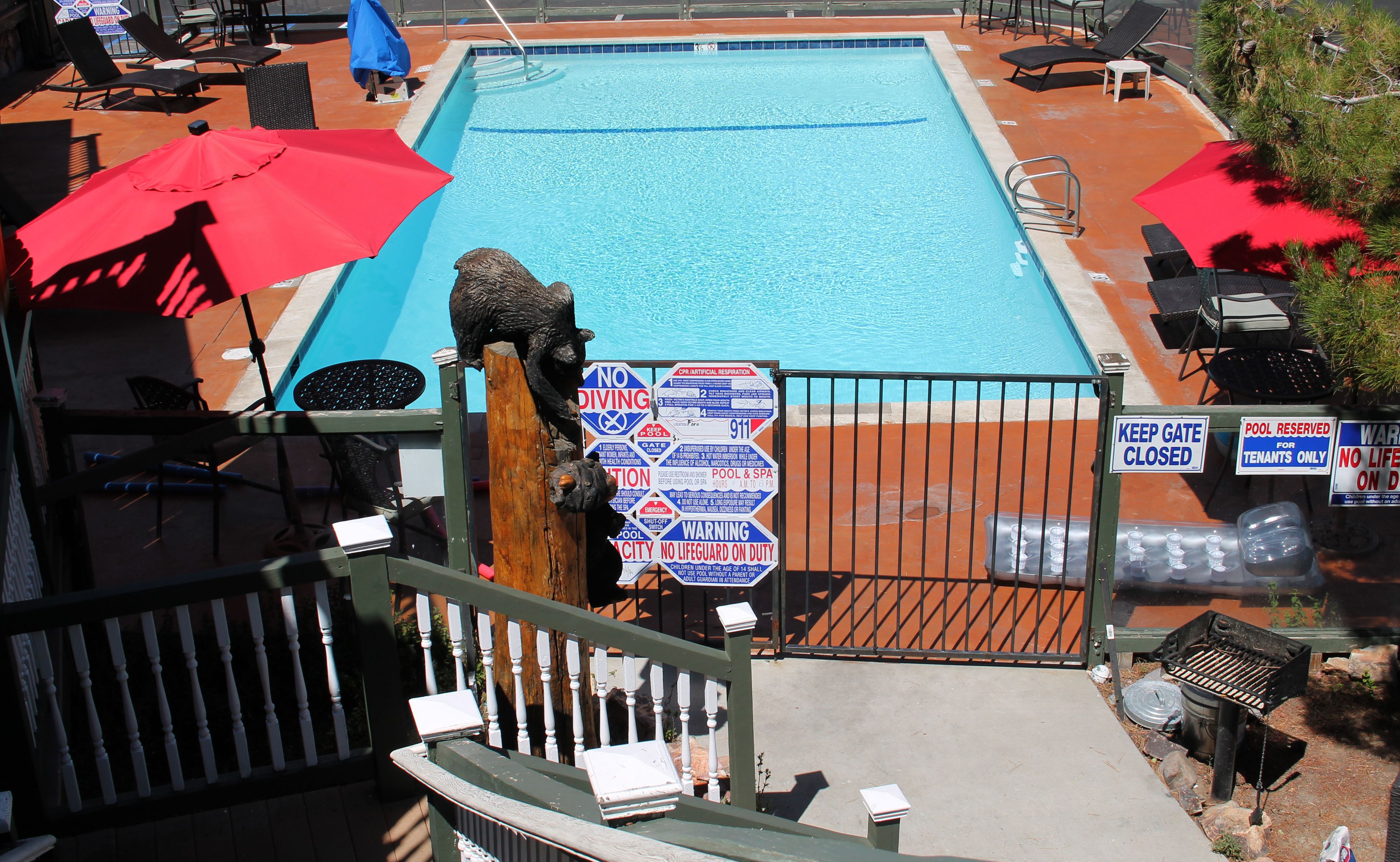 A swimming pool with a lifeguard statue, surrounded by lounge chairs and umbrellas.