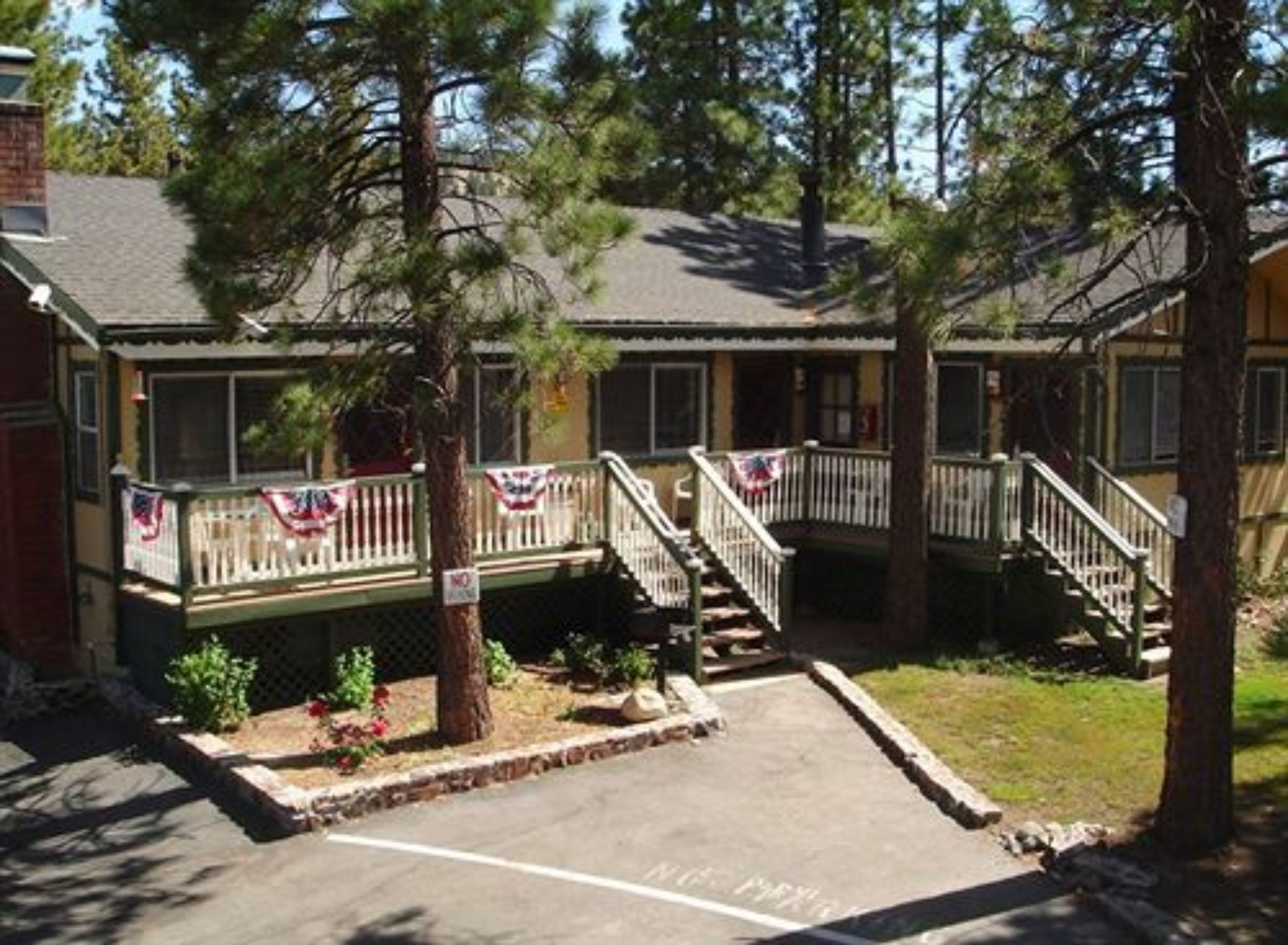 A motel with a covered porch, a parking area, and a flag decoration.
