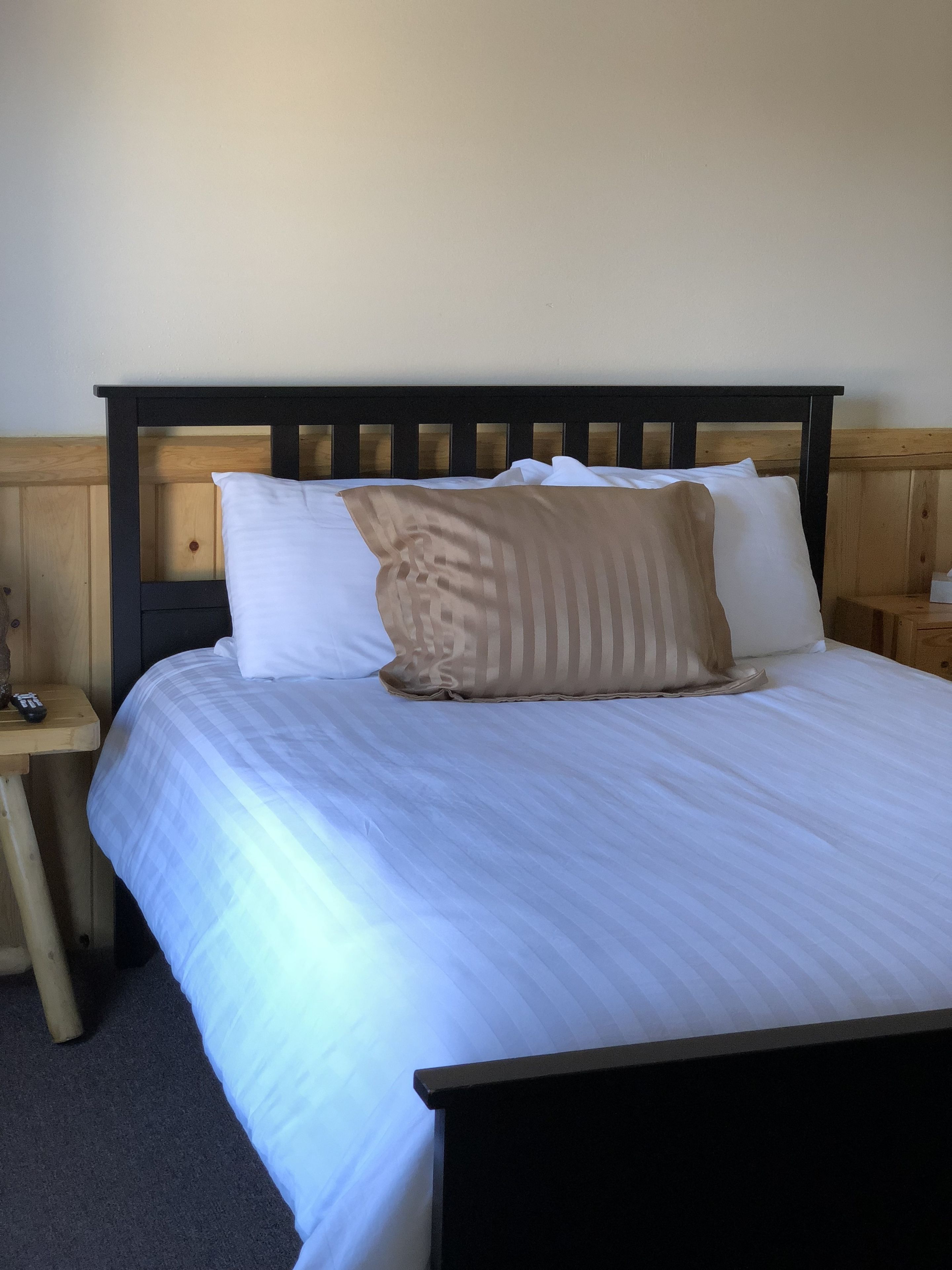 Ein Bett mit weißer Bettwäsche und einem Holz-Kopfteil.