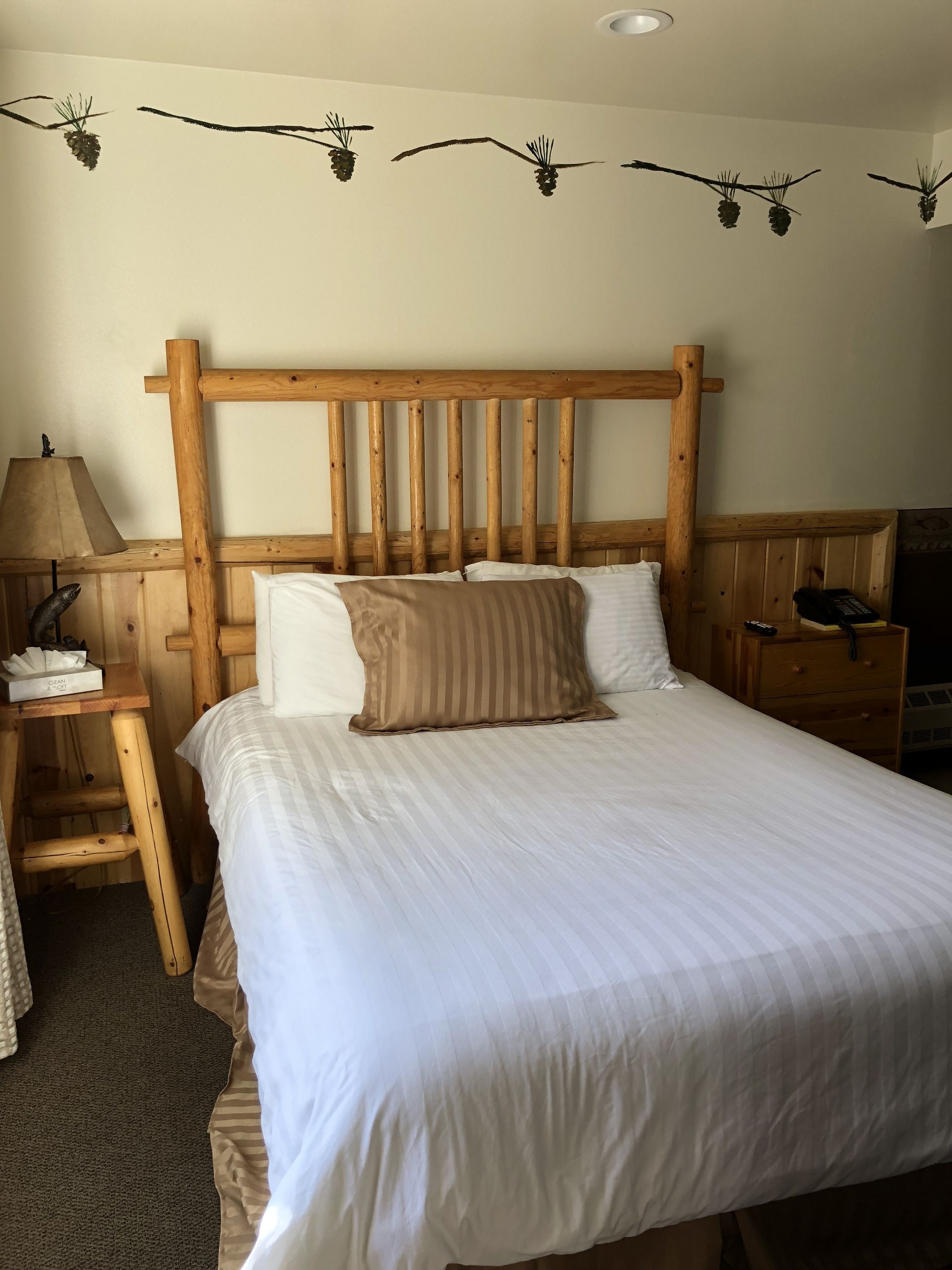 A wooden bed with a headboard, white bedding, and a lamp on a bedside table.