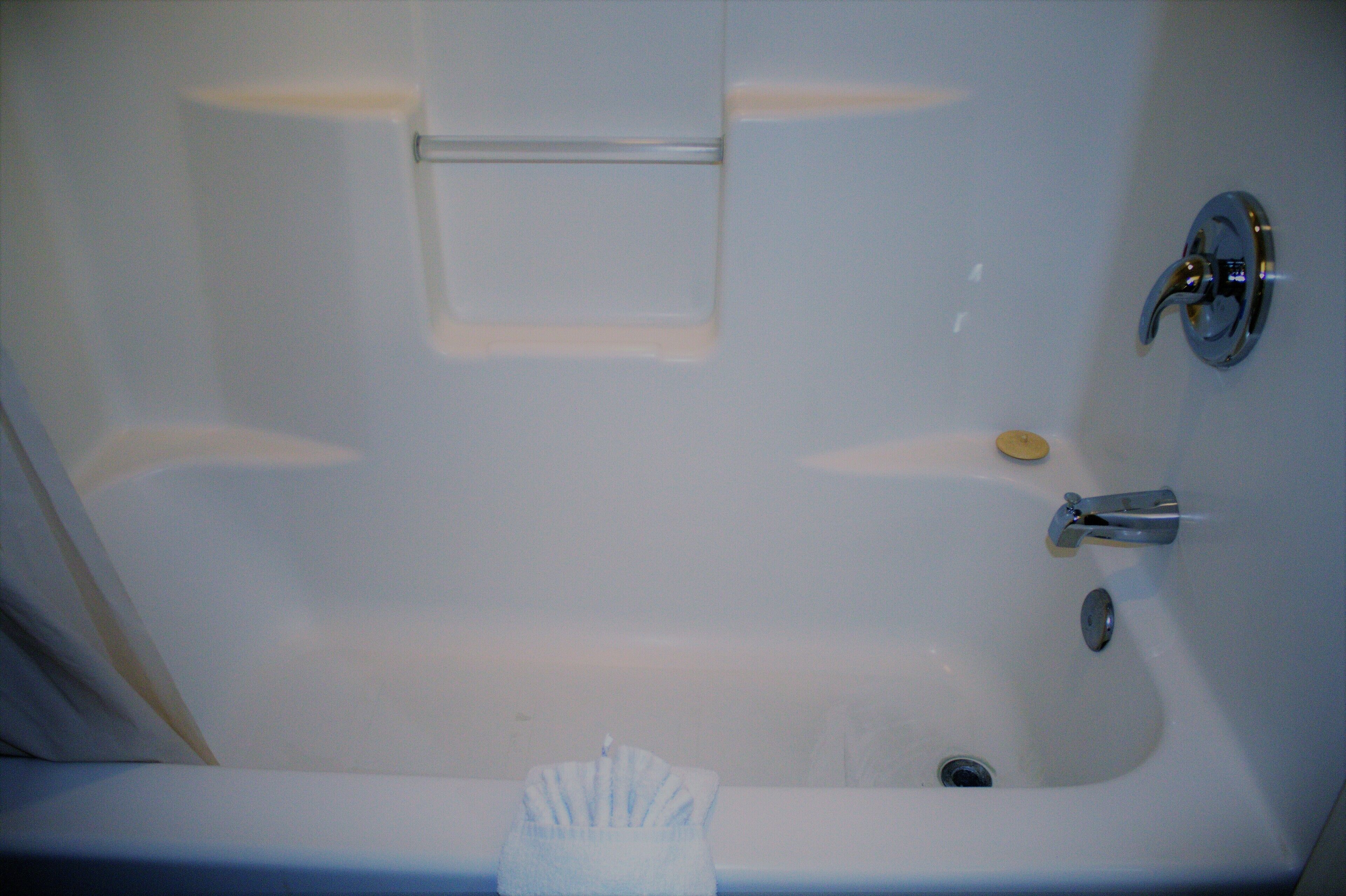 A white bathtub with a single faucet and a soap dish.