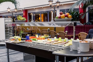 Un buffet proposant divers plats, avec un espace réservé aux convives en arrière-plan.
