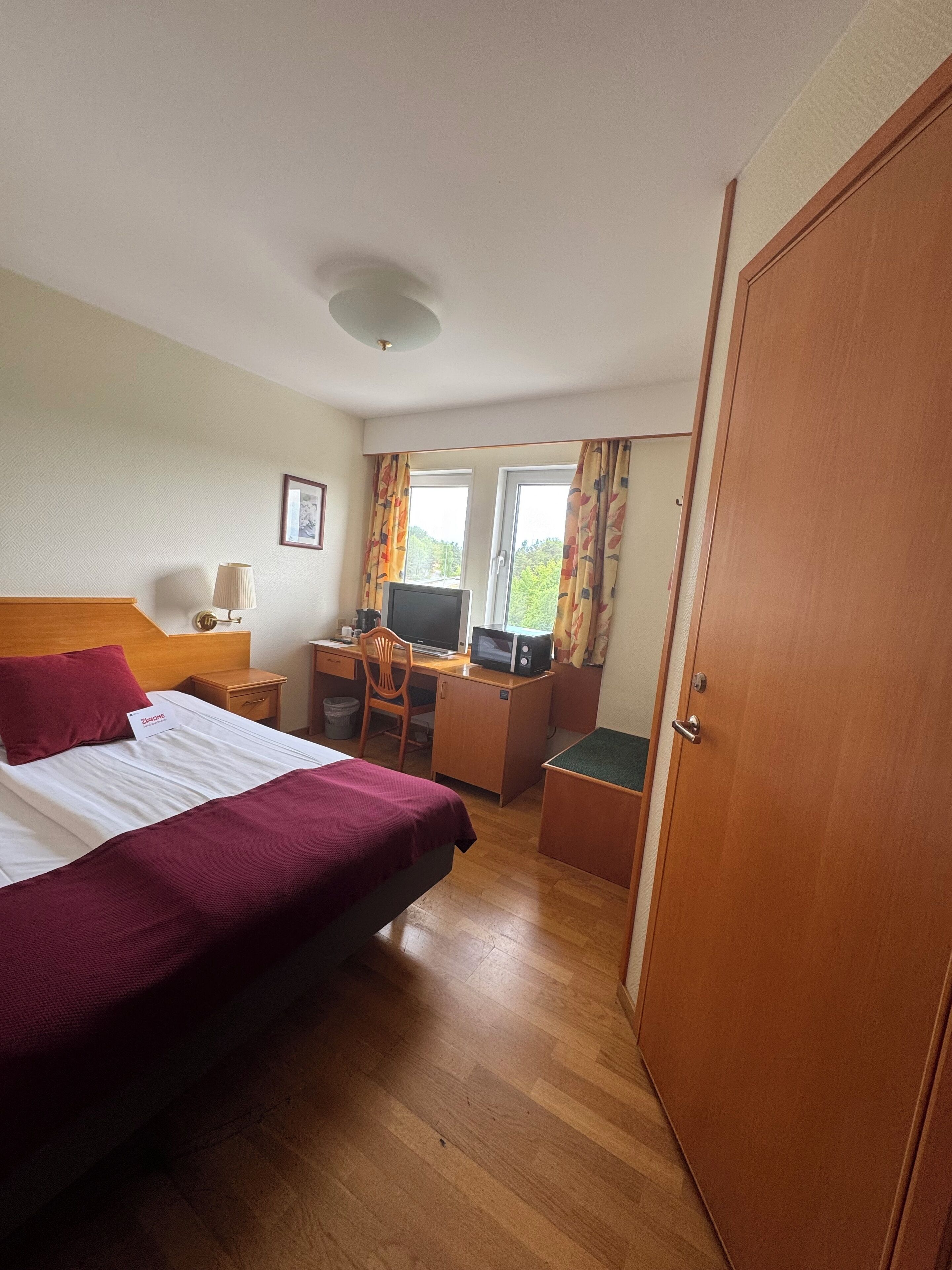 Een hotelkamer met een bed, bureau, stoel en een televisie.
